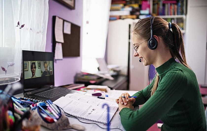 Frau mit Headset vor dem Laptop bei einer Videokonferenz Frau mit Headset vor dem Laptop bei einer Videokonferenz