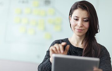 Frau mit Tablet vor einem Whiteboard