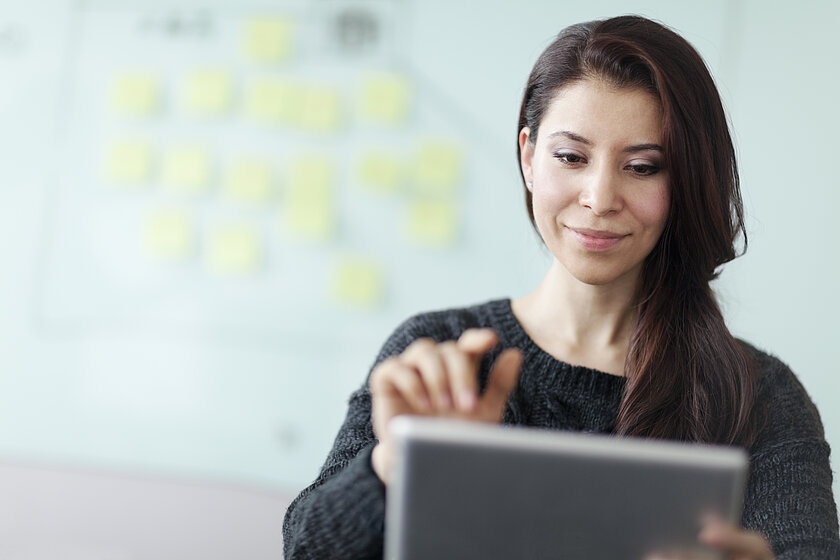Frau mit Tablet vor einem Whiteboard