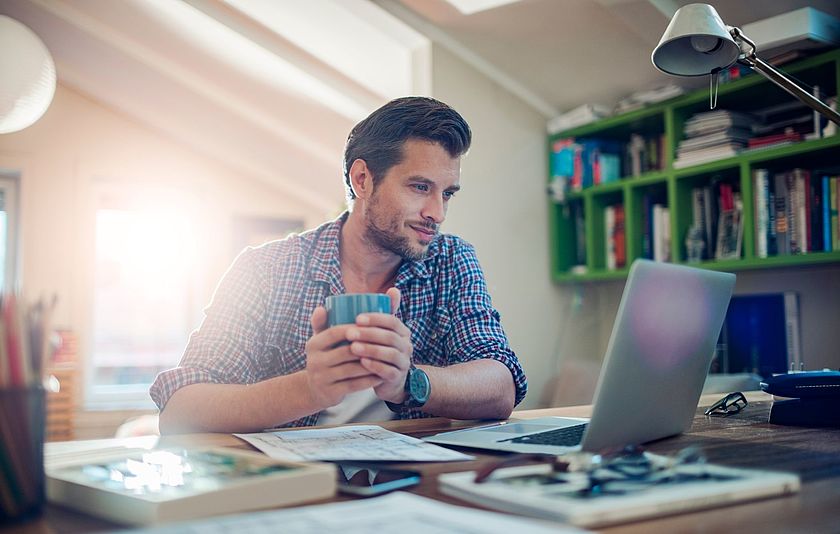 Lehrer schaut auf seinen Laptop im Arbeitszimmer