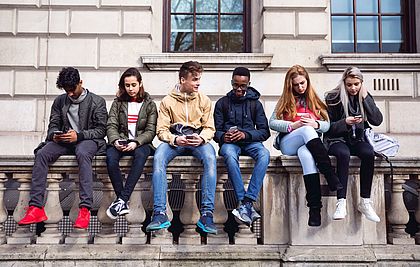 Jugendliche sitzen nebeneinander auf einer Mauer