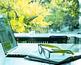 Laptop, Buch und Brille auf einem Schreibtisch