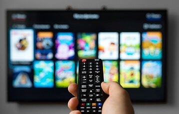 Hand hält Fernbedienung für SmartTV