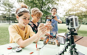 Teenager mit Roboter und Handykamera