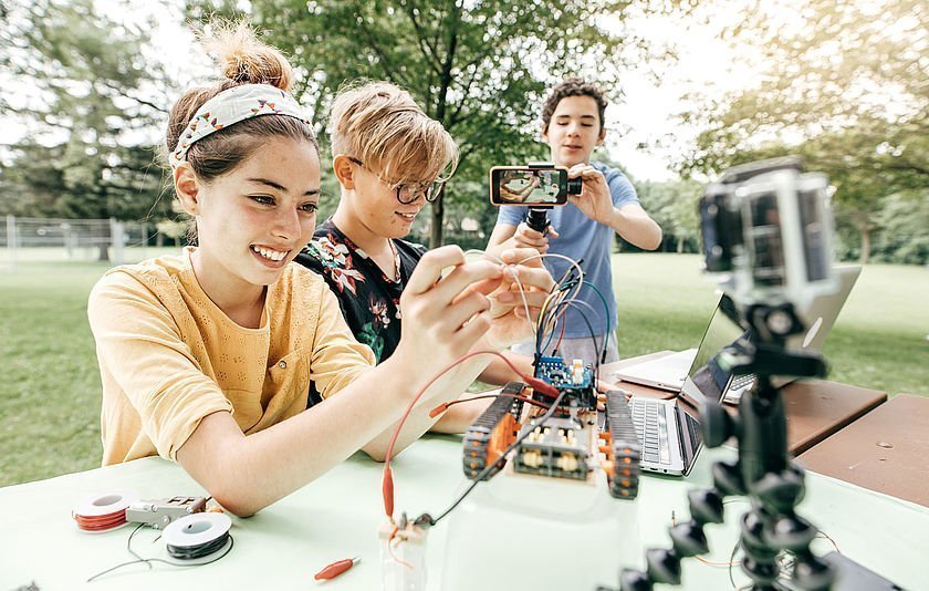 Teenager mit Roboter und Handykamera