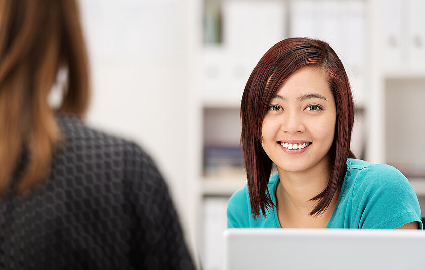 Lächelnde Schülerin vor ihrem Laptop.