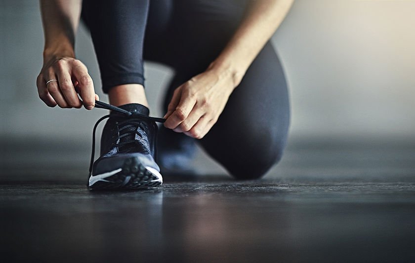 Frau bindet sich den Sportschuh Frau bindet sich den Sportschuh