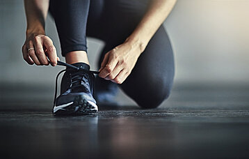 Frau bindet sich den Sportschuh