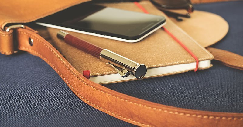 Tasche mit Smartphone und Notizbuch