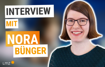 Links steht der Text:Interview mit Nora Buenger. Rechts sieht man Nora Buenger, eine Frau mit braunen kuerzeren Haaren und Brille, die laechelt.