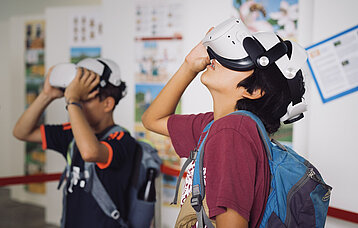 Zwei Jungen schauen mit einer VR-Brille an die Decke.