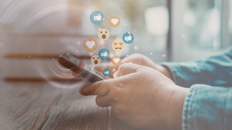 Im Zentrum des Bildes ist ein Smartphone in zwei Händen zu sehen. Die Hände interagieren auf dem Display und aus dem Smartphone gelangen Emojis und Likes nach oben. Transparent ist ein Schallkreis zu erkennen, der am Smartphone entsteht. Sinnbildliches Bildensemble für die "Polarisierungsschleife"