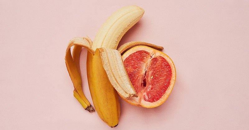 Halb geschälte Banane neben einer halben Grapefruit