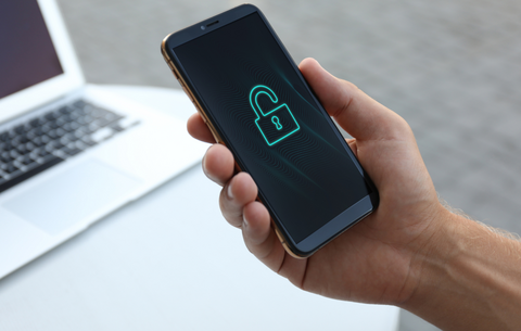 Ein Smartphone in einer Hand, auf dessen Bildschirm ein Sperrsymbol zu sehen ist.