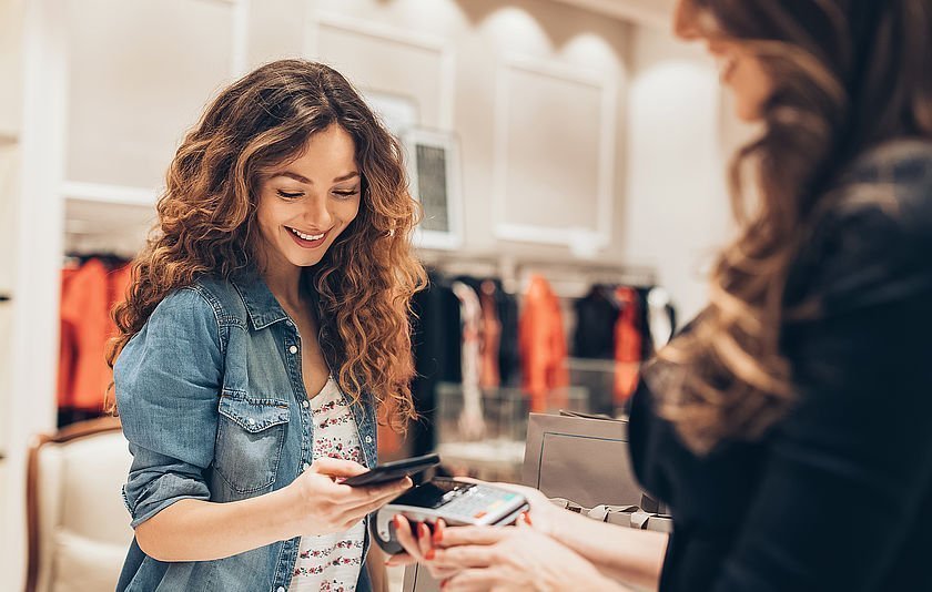 Junge Frau bezahlt mit dem Smartphonee