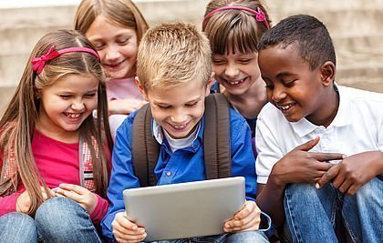 Fünf Grundschüler sehen auf ein Tablet