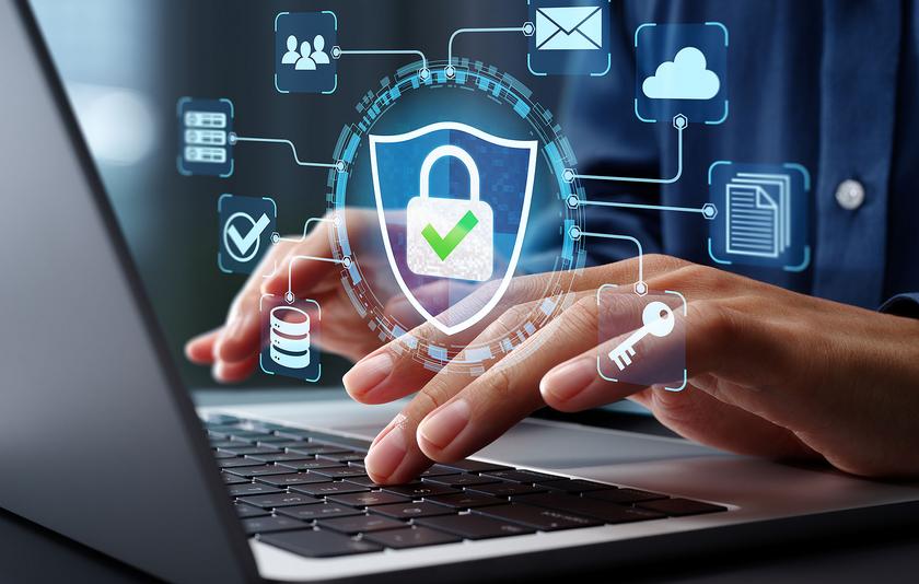 Man sieht einen aufgeklappten Laptop, darüber tippende Hände. Über dem Foto lagert eine Grafik mit einem Sicherheitsschloss, ein Symbol für eine Firewall.