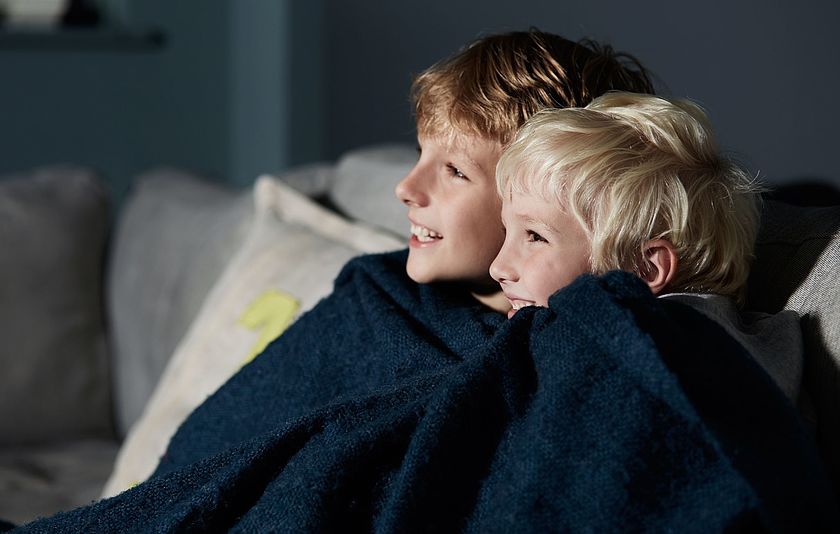 Zwei Jungs unter einer Decke auf dem Sofa