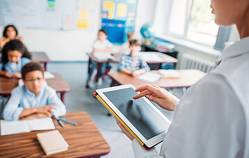 Lehrer mit Tablet vor der Schulklasse