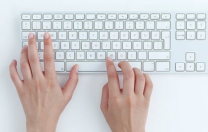 Hände mit weißer PC-Tastatur