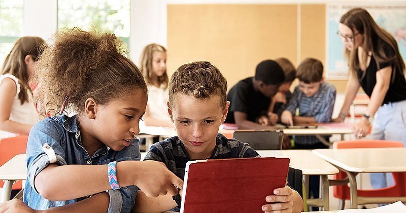 Zwei Schulkinder mit Tablet im Klassenzimmer