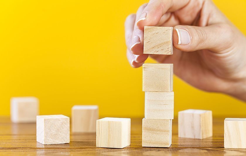 Hand baut einen Turm aus Holzklötzen
