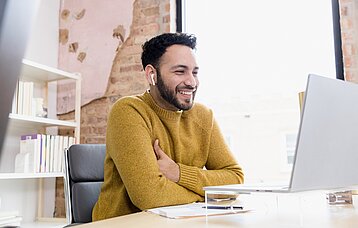 Ein Mann sitzt vor seinem Laptop und nimmt an einer Online-Veranstaltung teil.