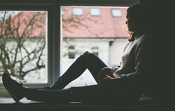 Mädchen sitzt auf einer Fensterbank