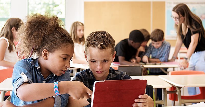 Zwei Schulkinder mit Tablet im Klassenzimmer