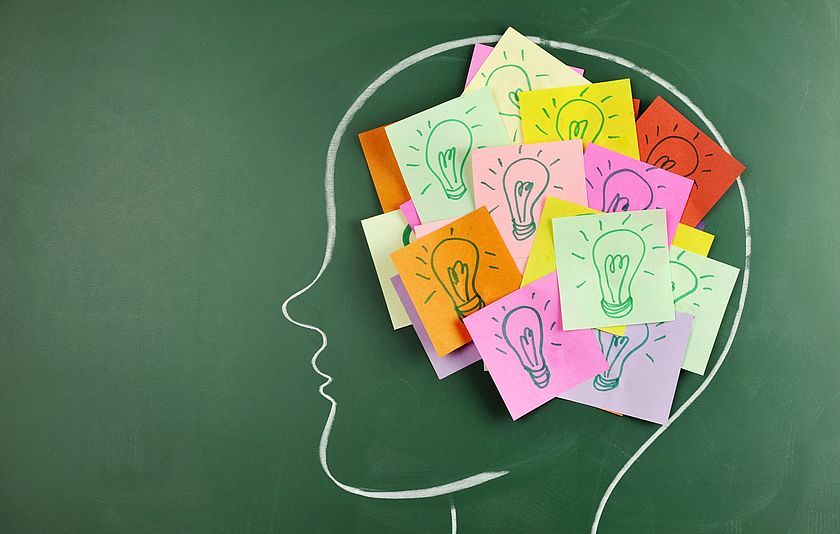 Kopfzeichnung auf einer Tafel mit Haftnotiz-Zetteln