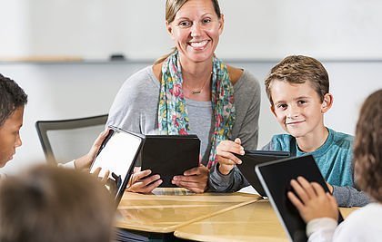 Lehrerin mit Schülern und Tablets