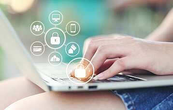Hände auf einem Laptop mit eingeblendeten Icons zum Thema Datenschutz