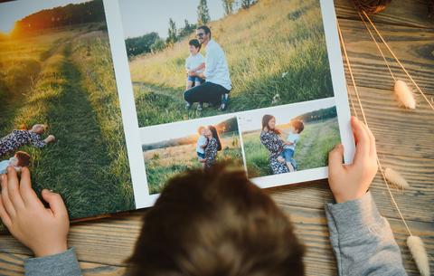 Ein Junge von hinten, der ein Fotoalbum der Familie anschaut.