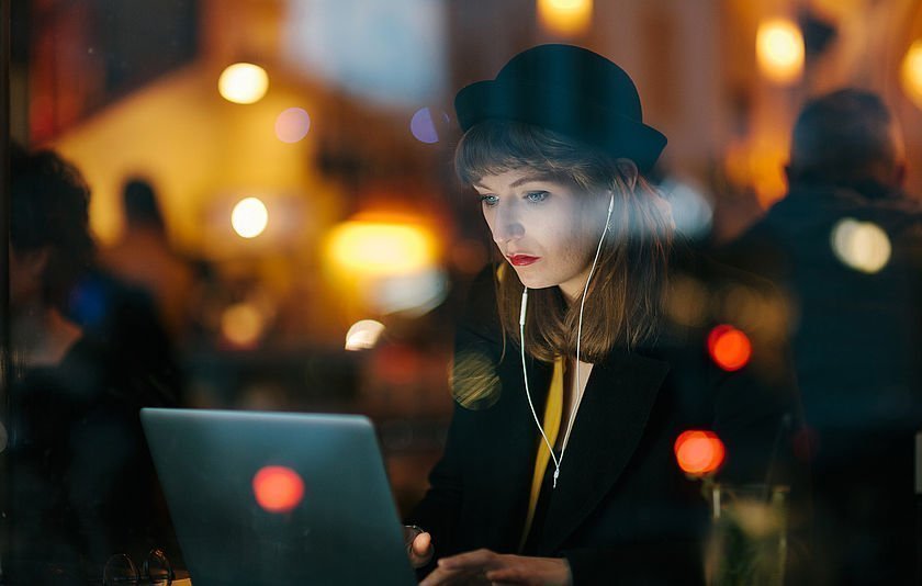 Frau vor Notebook mit Kopfhörer im Dunkeln Frau vor Notebook mit Kopfhörer im Dunkeln