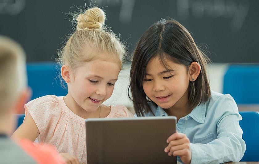 Zwei Grundschülerinnen schauen auf ein Tablet Zwei Grundschülerinnen schauen auf ein Tablet