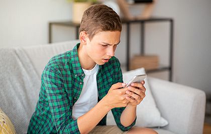 Teenager schaut auf sein Smartphone.