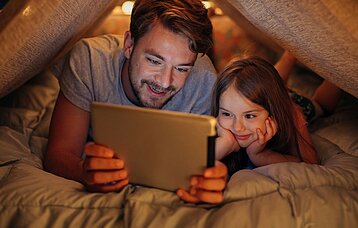 Vater liest Tochter am Tablet vor