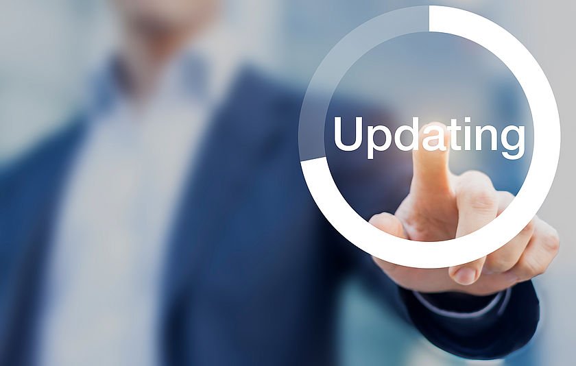 Junger Mann, der einen Updatebutton drückt.