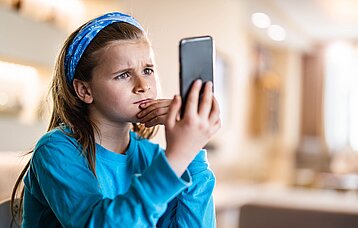Mädchen schaut in ein Smartphone.