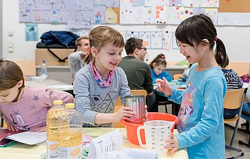 Grundschülerinnen experimentieren im Unterricht.