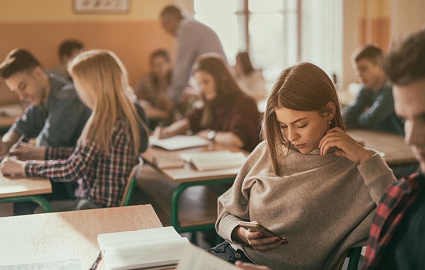 Schülerin mit Handy im Unterricht.