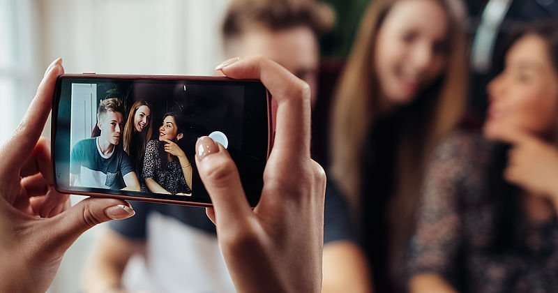 Drei Jugendliche werden mit einem Smartphone fotografiert