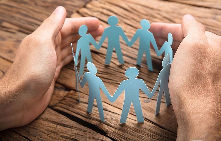 Zwei Hände legen sich um einen aus Papier ausgeschnittenen Kreis von Figuren Illustration eines Handys mit Jugendschutz-Filter