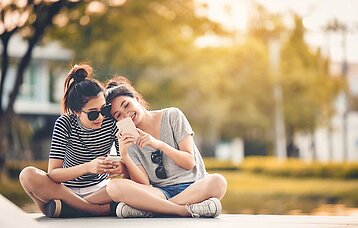 Zwei Mädchen mit Smartphones im Park