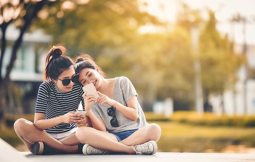 Zwei Mädchen mit Smartphones im Park
