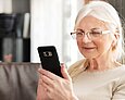 Ältere Dame liest Nachrichten auf ihrem Handy.