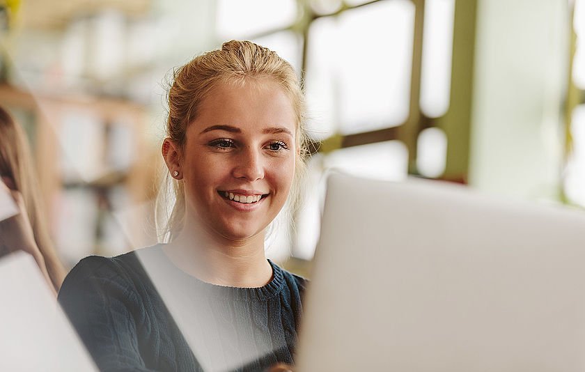 Mädchen sitzt lächelnd am PC