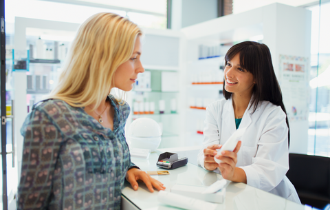 Beratung in der Apotheke mithilfe der ePA Eine junge Frau steht am Tresen einer Apotheke und lässt sich von einer anderen jungen Frau zu einem Medikament beraten.