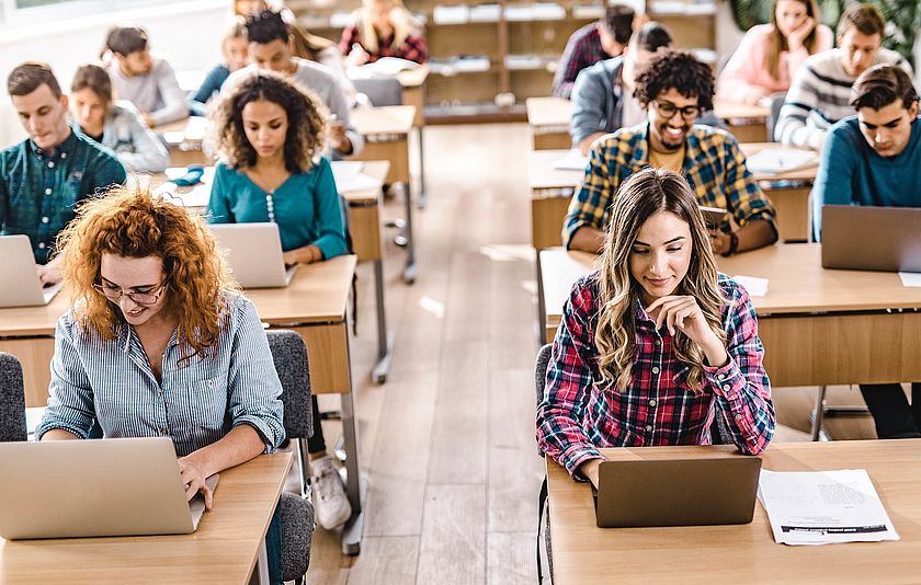 Klassenzimmer mit Schülerinnen und Schülern am Notebook.