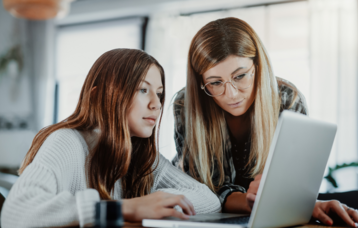 Mutter und Tochter schauen auf einen Laptop